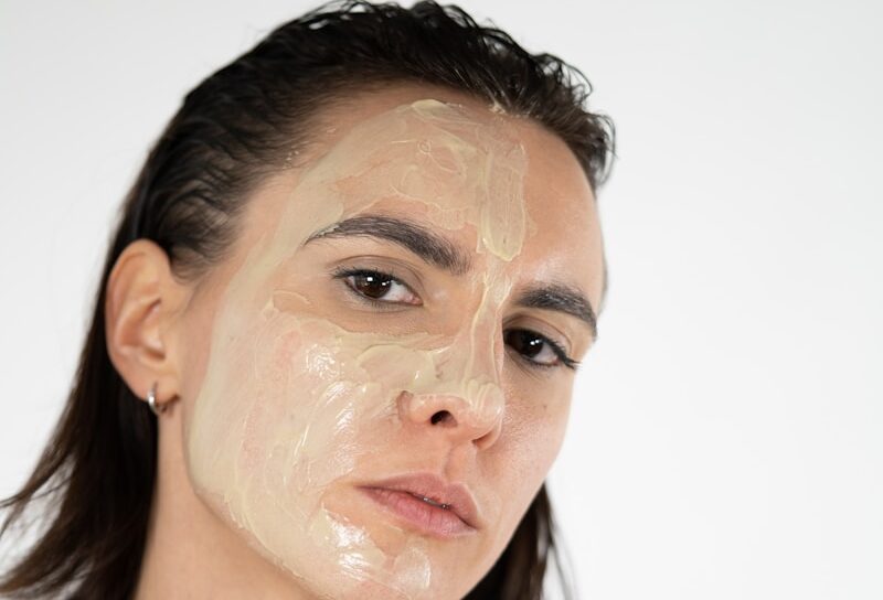 a woman holding a jar of cream on her face